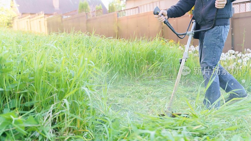 Man MOWS grass with trimmer, focus on前景模糊的背景